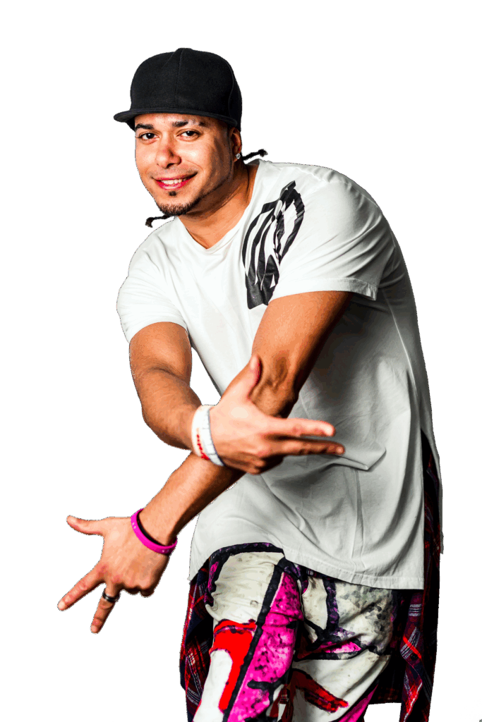 Homme en tenue streetwear avec casquette noire et pantalon coloré, posant dans un style hip-hop avec un large sourire.